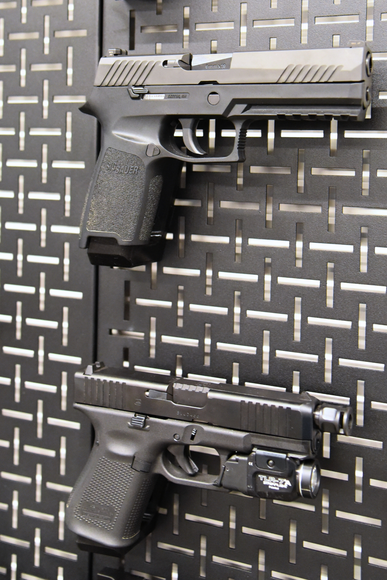 Two pistols mounted on a black SpartanGrid panel